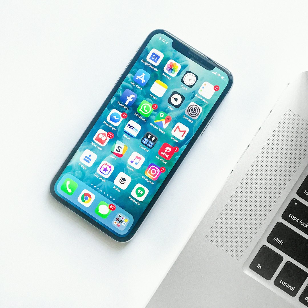 Smartphone dan laptop di meja kerja, melambangkan bermain dari perangkat seluler